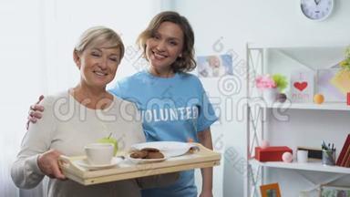 社工抱着拿着餐盘的退休妇女，义工<strong>来访</strong>